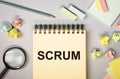Scrum word on notepad on office desk, flat lay. Concept of method in management