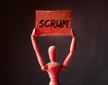 Scrum word on placard in wooden businessman hands. Concept of methods in management