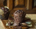 Scrumptious Home Baked Chocolate Chips Muffins in Brown Paper on Wooden Cutting Board. Cocoa in Spoon. Rustic Kitchen