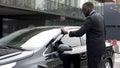 Scrupulous Afro-American man wiping his new car before leaving parking lot Royalty Free Stock Photo