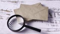 Scrutinizing Correspondence: Magnifying Glass and Stack of Brown Envelopes on Wood Royalty Free Stock Photo