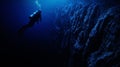 scuba diver at the edge of a drop-off, endless deep blue abyss, feeling of awe and solitude. Royalty Free Stock Photo