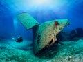 A scuba diver explores a sunken shipwreck in shallow waters