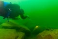 SCUBA diver exploring a cloudy inland lake and boulders with a diving torch