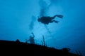 Scuba diver hover over a shipwreck in silhouette