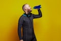 Scuba diver man drinking on yellow studio wall background