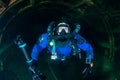 Scuba diver with a rebreather, drysuit and camera swimming through an underwater tunnel Royalty Free Stock Photo