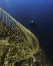 Scuba diver swimming near fishing net