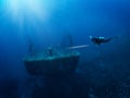 A scuba diver with a torch explores a sunken shipwreck Royalty Free Stock Photo