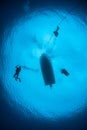 Scuba Divers Descending into Blue Water