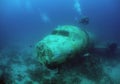 scuba divers and a plane are in the ocean water near a wreck Royalty Free Stock Photo