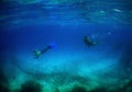 Scuba divers swimming among the fish in the beautiful blue ocean