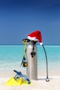 Scuba diving gear with a red Santa hat on a tropical beach