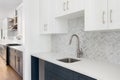 A scullery or butler\'s pantry detail with a bronze faucet and herringbone tile backsplash.