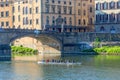 Sculling boat on the river at an old bridge in Florence