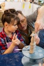 Teacher helping cute pupil sculpting clay animal at art lesson