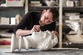 The sculptor conducts restoration work in a plaster workshop. Restoration of the gypsum head of Apollo