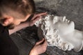 The sculptor conducts restoration work in a plaster workshop. Restoration of the gypsum head of Apollo