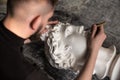 The sculptor conducts restoration work in a plaster workshop. Restoration of the gypsum head of Apollo