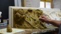 Sculptor create clay model of a Corinthian capitel with scrolls and unfurled acanthus leaves in restoration workshop