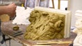 Sculptor create clay model of a Corinthian capitel with scrolls and unfurled acanthus leaves in restoration workshop