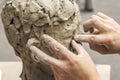 sculptor creates a bust and puts his hands clay on the skeleton of the sculpture