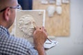 A sculptor sculpts a sculpture of a person`s face. Horizontal frame