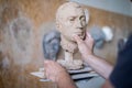 A sculptor sculpts a sculpture of a person`s face. Horizontal frame