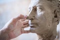 A sculptor sculpts a sculpture of a person`s face. Horizontal frame