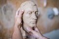 A sculptor sculpts a sculpture of a person`s face. Horizontal frame