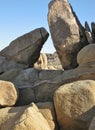 Sculptural granite boulders against a blue sky, forming a triangular window to the desert landscape beyond