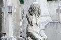 Sculpture of a angel girl in an old cemetery. Closeup of stoned angel with closed eyes and cross monument at cemetery. Graveyard