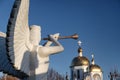 Sculpture of angel with a wind instrument against the background of the Orthodox Church Royalty Free Stock Photo