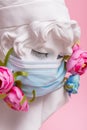 Sculpture of antique girl made of plaster in medical mask with flowers against pink background coronavirus pandemic