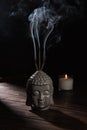 Sculpture of buddha head with burning incense sticks and candle Royalty Free Stock Photo