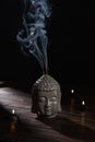 Sculpture of buddha head with burning incense sticks and candles Royalty Free Stock Photo