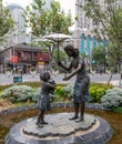Sculpture of Chinese mother holding umbrella for jewish little girl with teddy bear