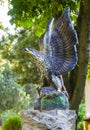 Sculpture Of An Eagle Made Of Stone On The Background Of Green Trees
