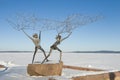 The sculpture `Fishermen` on the background of the frozen Onega lake