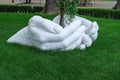 Sculpture of a hand made of plaster against a background of green lawn.