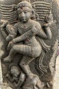 Sculpture of a Hindu God with a baby in the bottom of the feet. Bas relief sculpture carved in the stone walls of Shiva temple