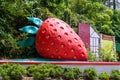 A sculpture of a huge red strawberry on the side of the road. Strawberry Farms District Symbol