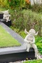 Sculpture of little angels sitting on stone beside colourful flowers