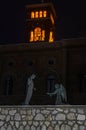 Sculpture with a man and angels on their knees on the embankment at night Nettuno, Italy