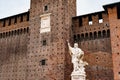 Sculpture of a man with a cross near the wall of Castello Sforzesco. Milan, Italy Royalty Free Stock Photo