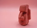 Sculpture of a Moai carved in volcanic stone from Easter Island Chile on a pink background