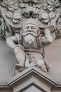 Sculpture of an old small and bearded funny man, dwarf, as an atlant in downtown of Magdeburg, Germany, closeup, details