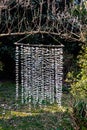 Sculpture of 1000 origami paper cranes hung from an overhead branch in a garden