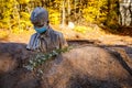 A sculpture of a pioneer in a mask on his face stands on a pile of sand. Solvay quarries Solvayovy lomy, Saint John under the