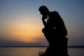 Sculpture thinking man in sunset silhouette. Concept photo Royalty Free Stock Photo